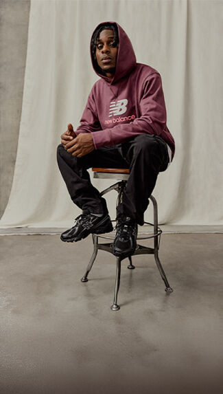 Person sitting on a stool, wearing new balance apparel and new balance 740 sneakers