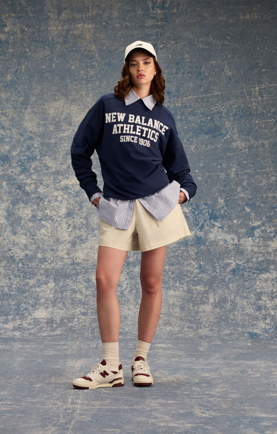 woman standing in a studio wearing new balance 550 sneakers & apparel