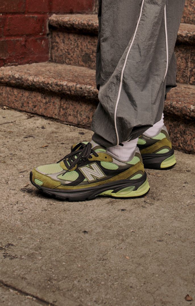 Side profile on figure shot of green, brown and black sneakers.