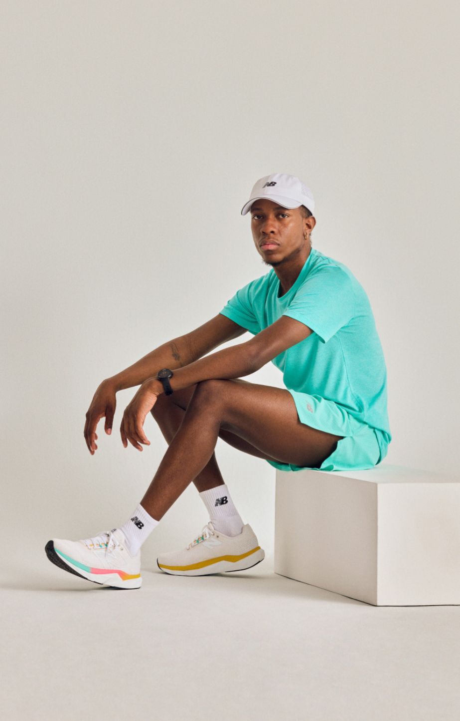man sitting on a block in a studio setting wearing New Balance propel runners and apparel