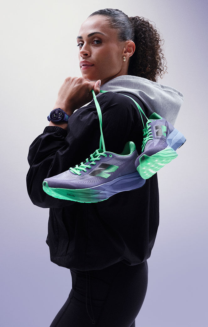 Sydney McLaughlin-Levrone holding a pair of shoes over her shoulder and looking towards the viewer.