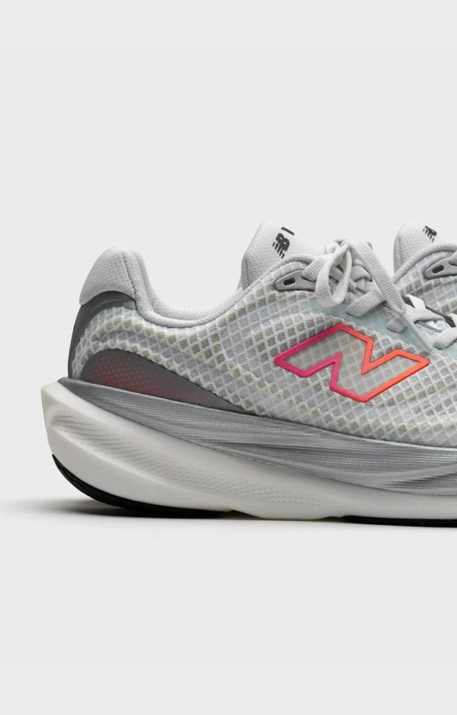 Cropped side view of a light gray New Balance running shoe on a neutral background, highlighting the mesh upper, sculpted midsole, and gradient &ldquo;N&rdquo; logo. 