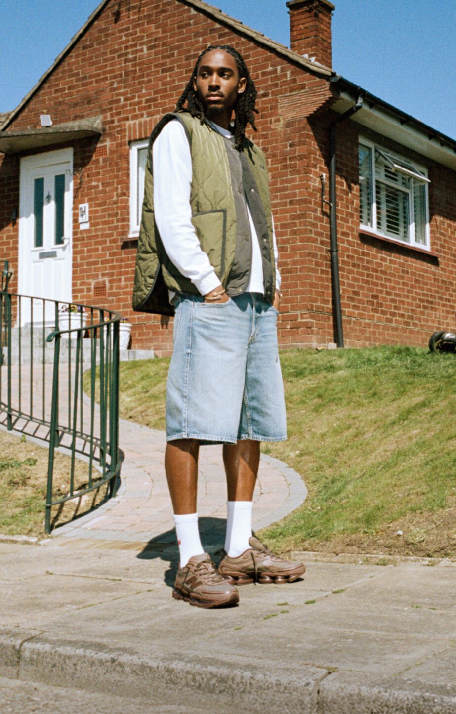 Knee-down image of someone wearing grey New Balance sneakers outdoors.