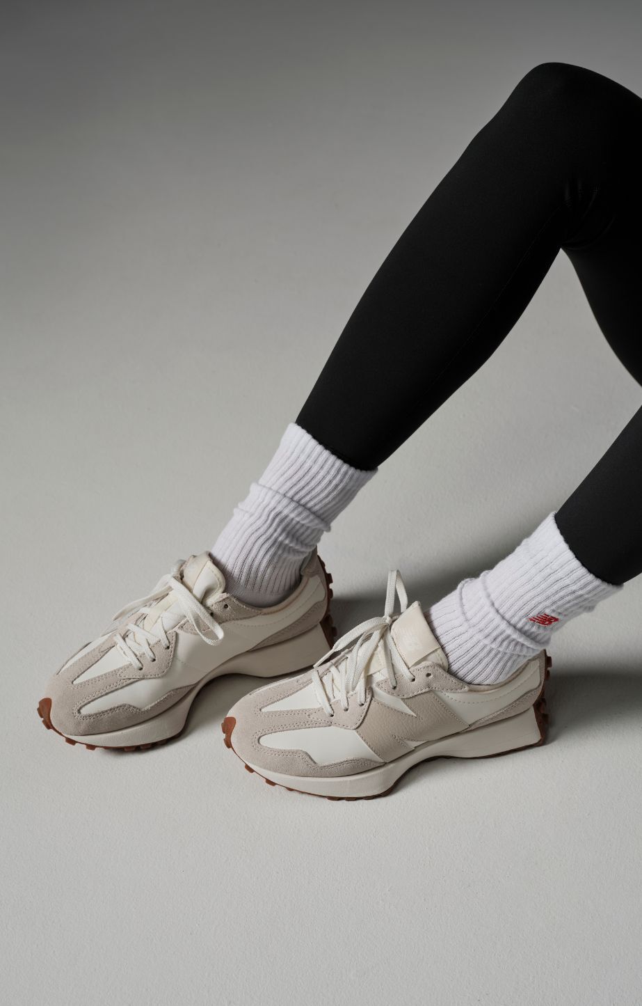 person sitting on the ground wearing new balance 327 sneakers