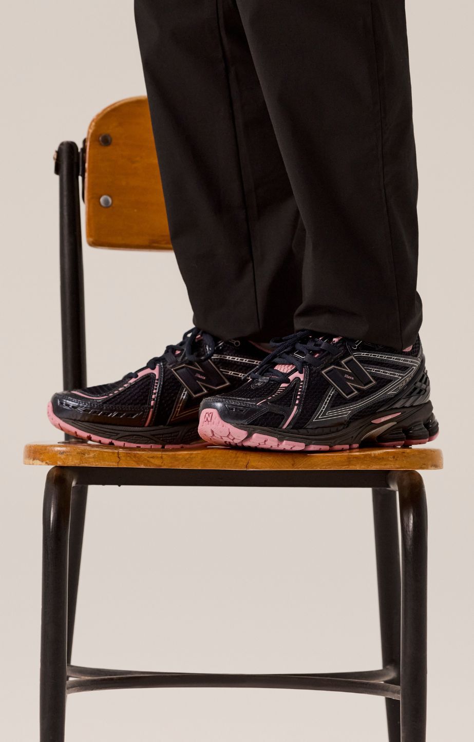 Person standing on a chair wearing new balance 1906 sneakers