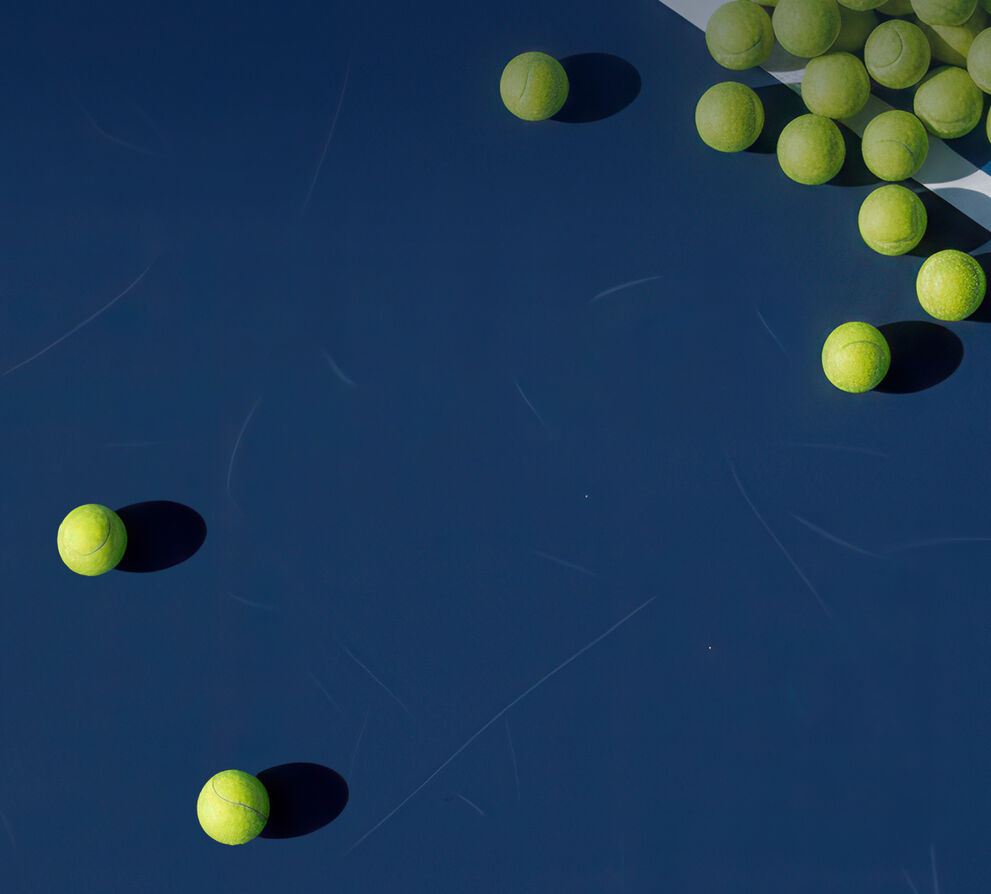 Tennis balls laying on a tennis court.
