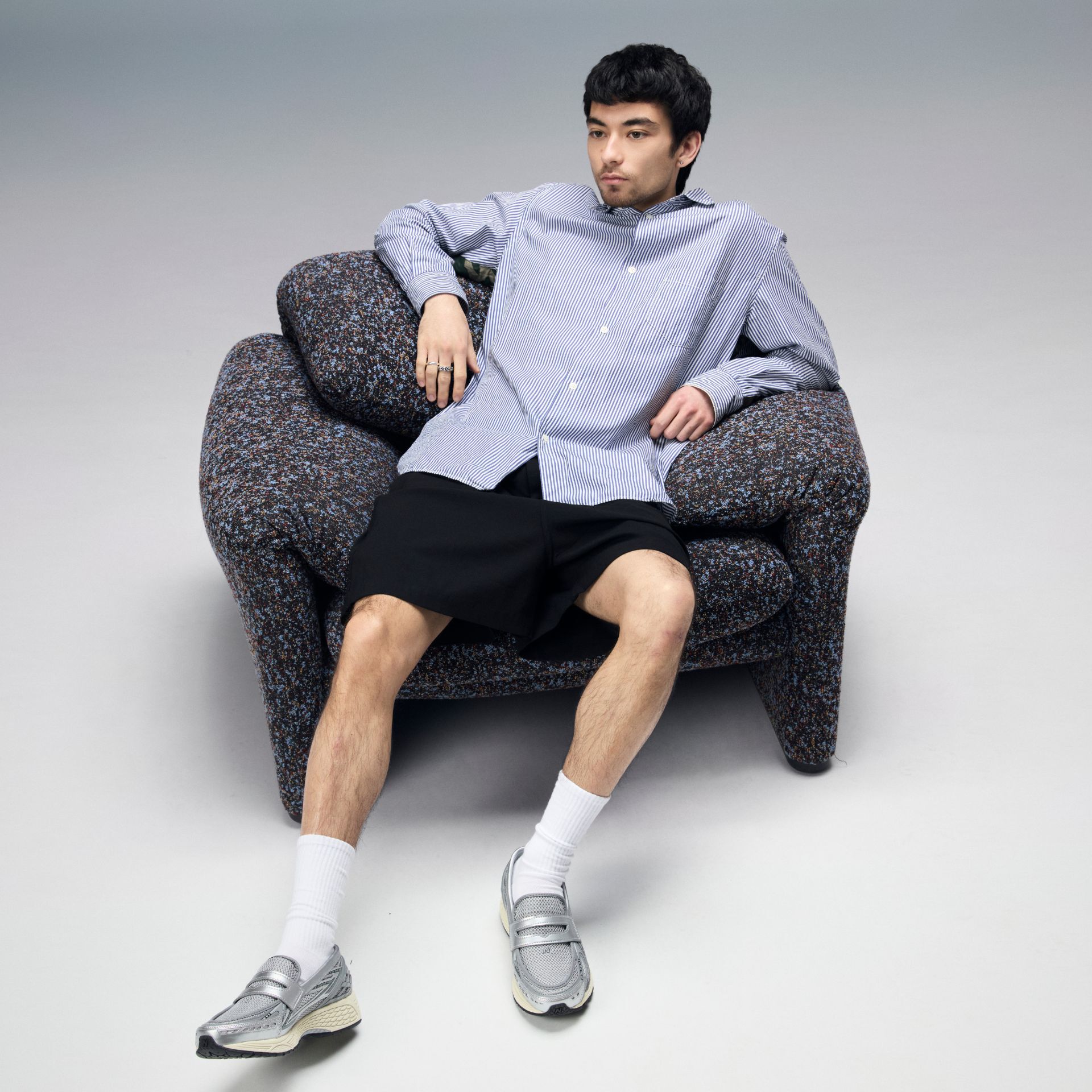 man sitting on a couch in a studio environment wearing 1906 loafers