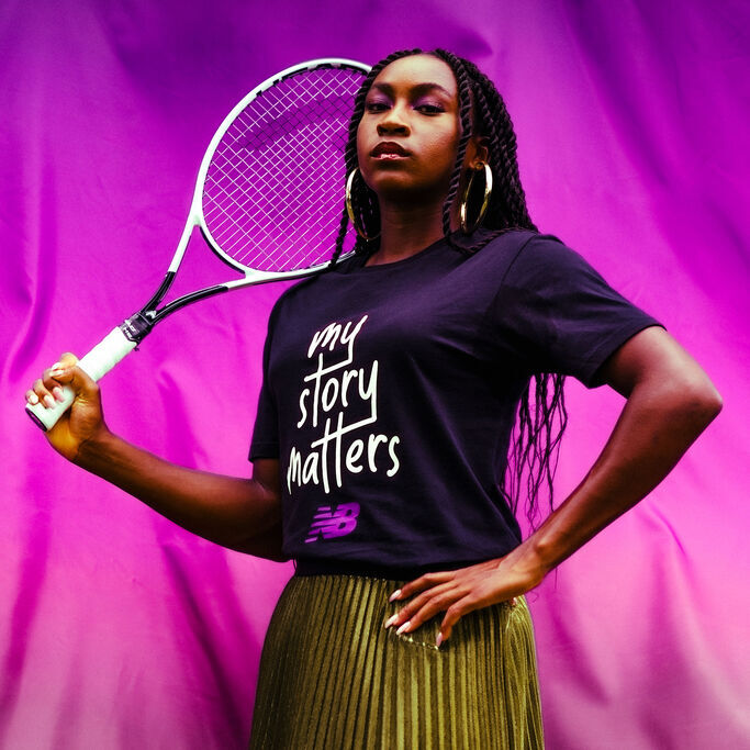 Coco Gauff standing holding a tennis racquet behind her head wearing New Balance shoes and apparel