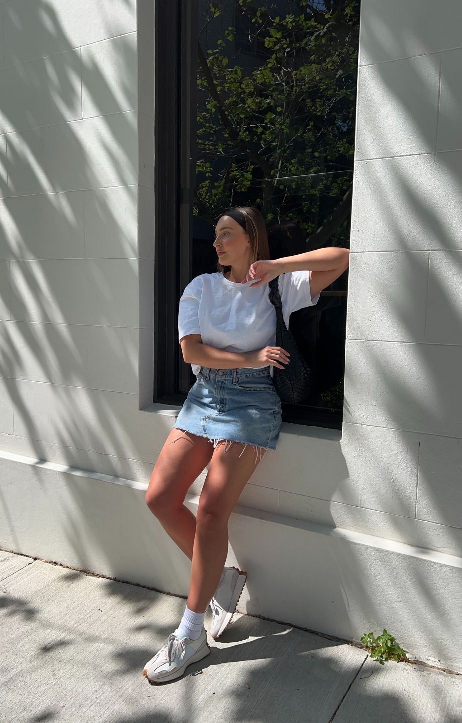woman leaning against wall wearing New Balance 327 shoes