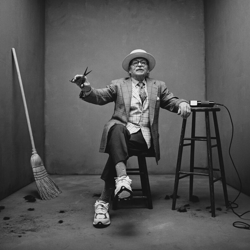 man sitting down with a pair of scissors in his hands