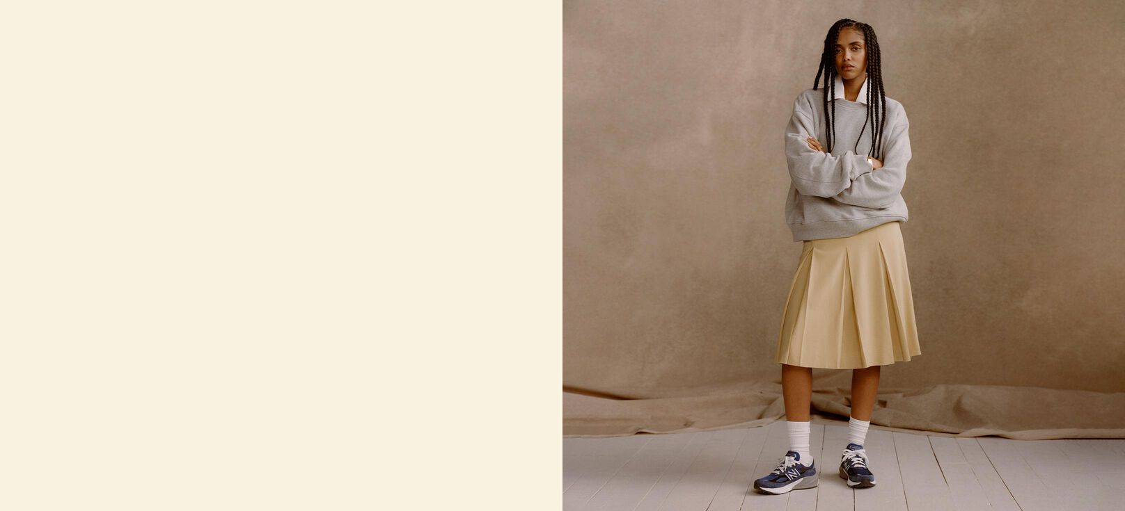  woman wearing blue Made in USA 990v6 shoes in front of a tan studio backdrop.