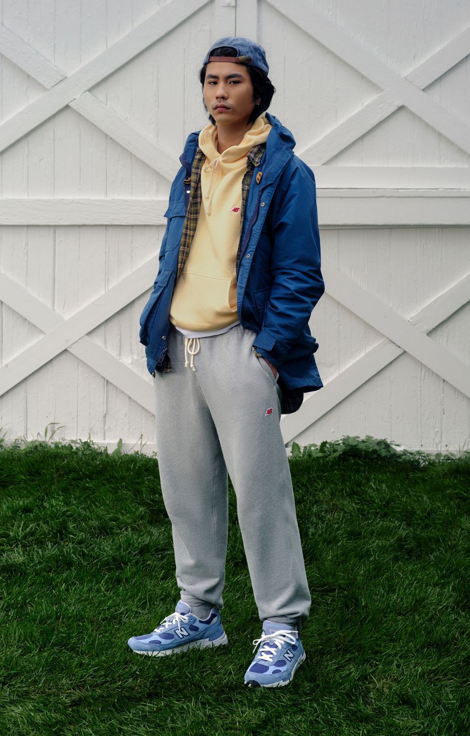 A man standing on the sand, holding made in usa 992 sneakers