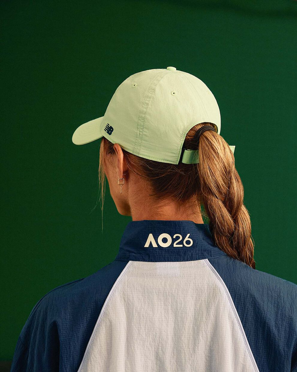 A person looking away from the camera, the Australian Open logo is displayed on the back of their jacket.
