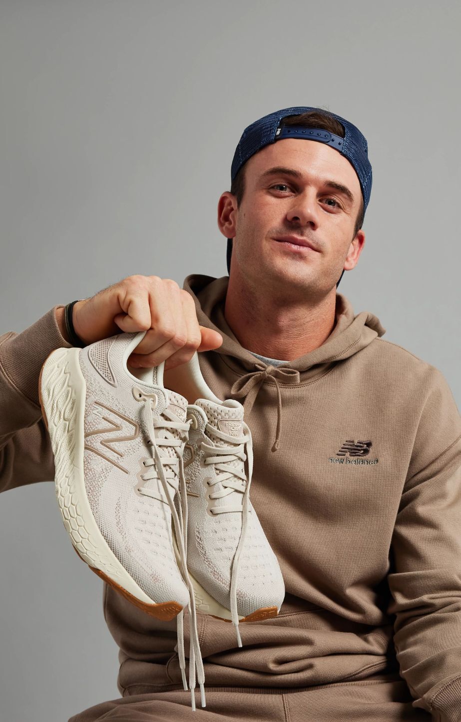 man holding a pair of New Balance 1080 runners and wearing New Balance clothing