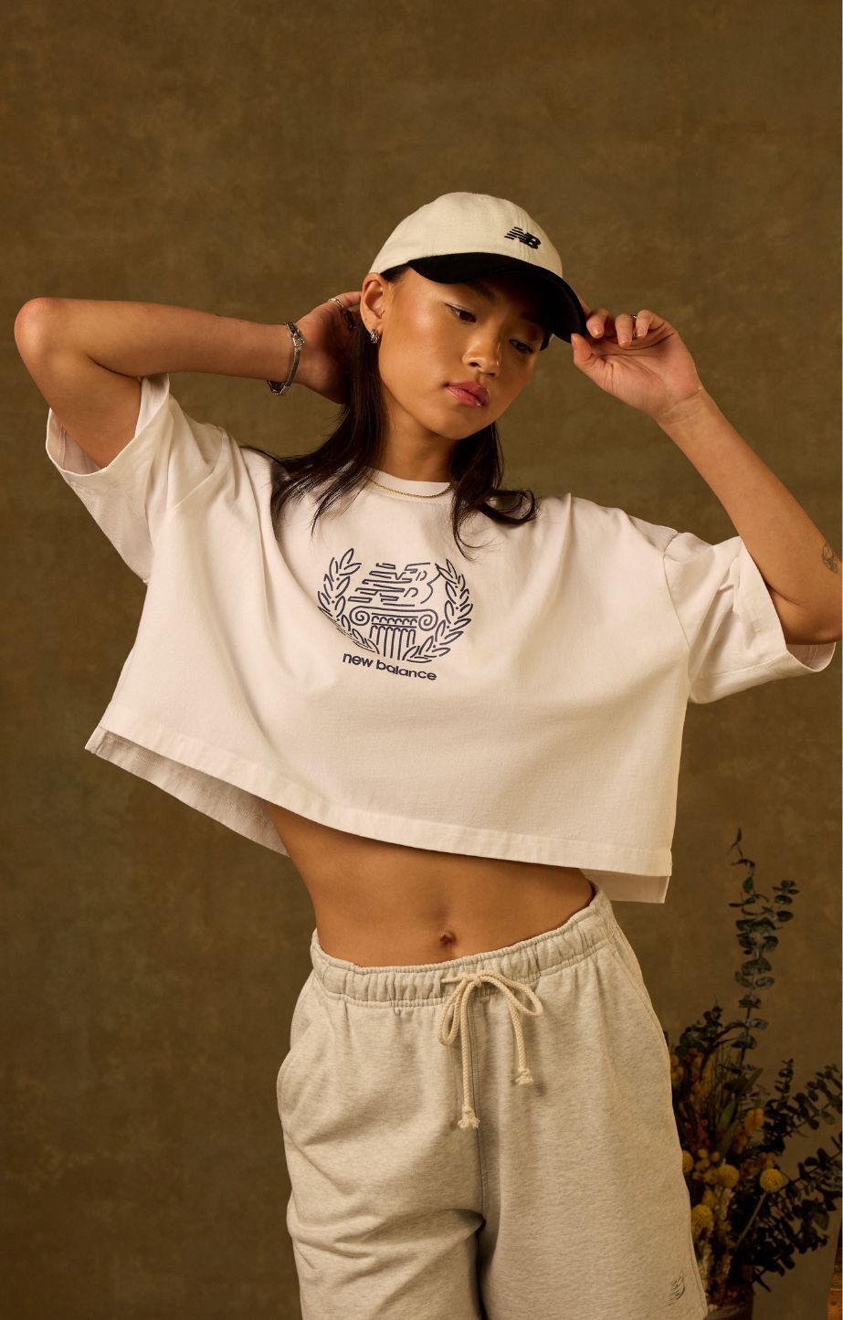 Woman standing against a dark background, wearing new balance apparel