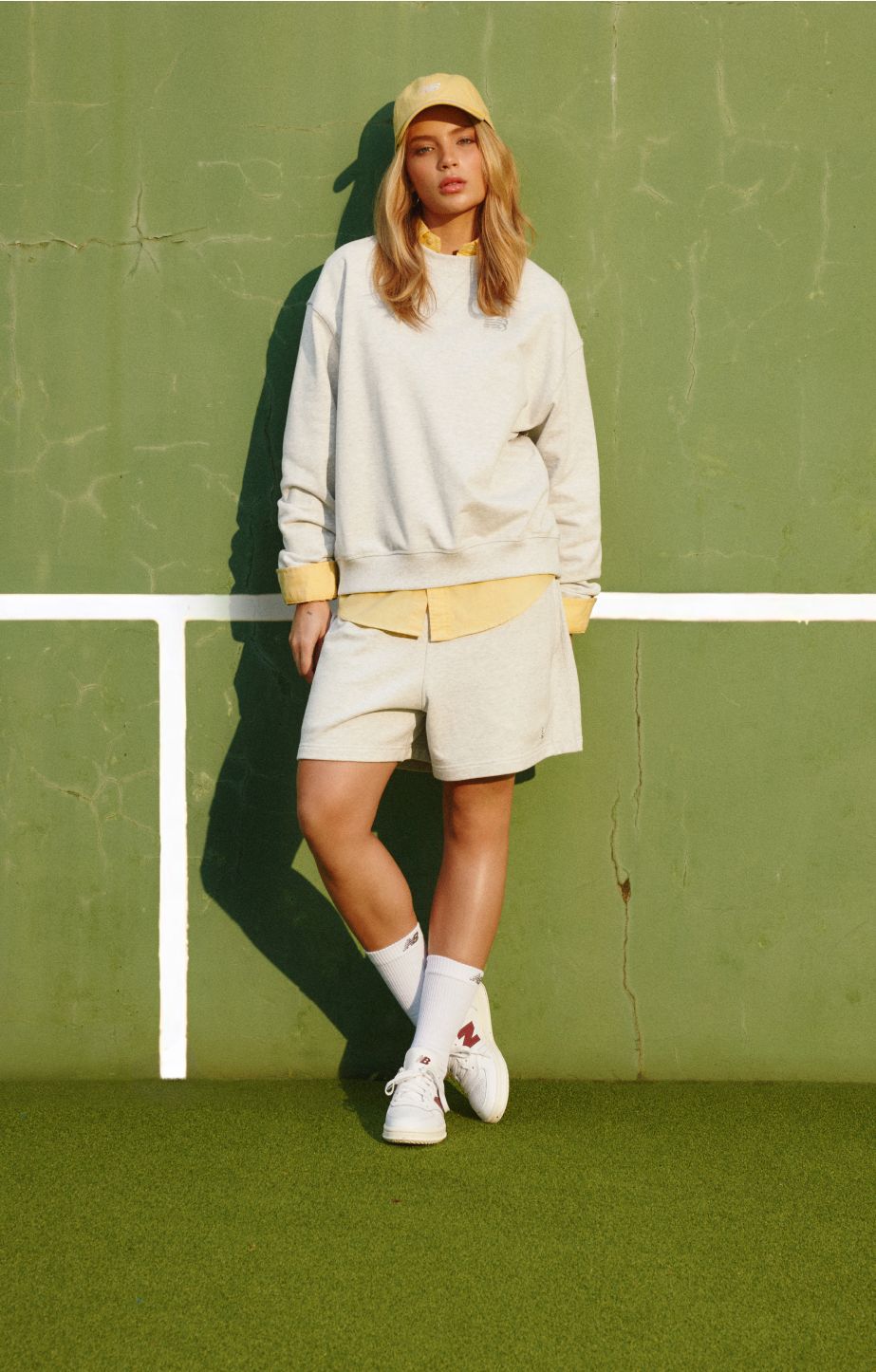Gabriely standing in a tennis court wearing New Balance T500 shoes. 