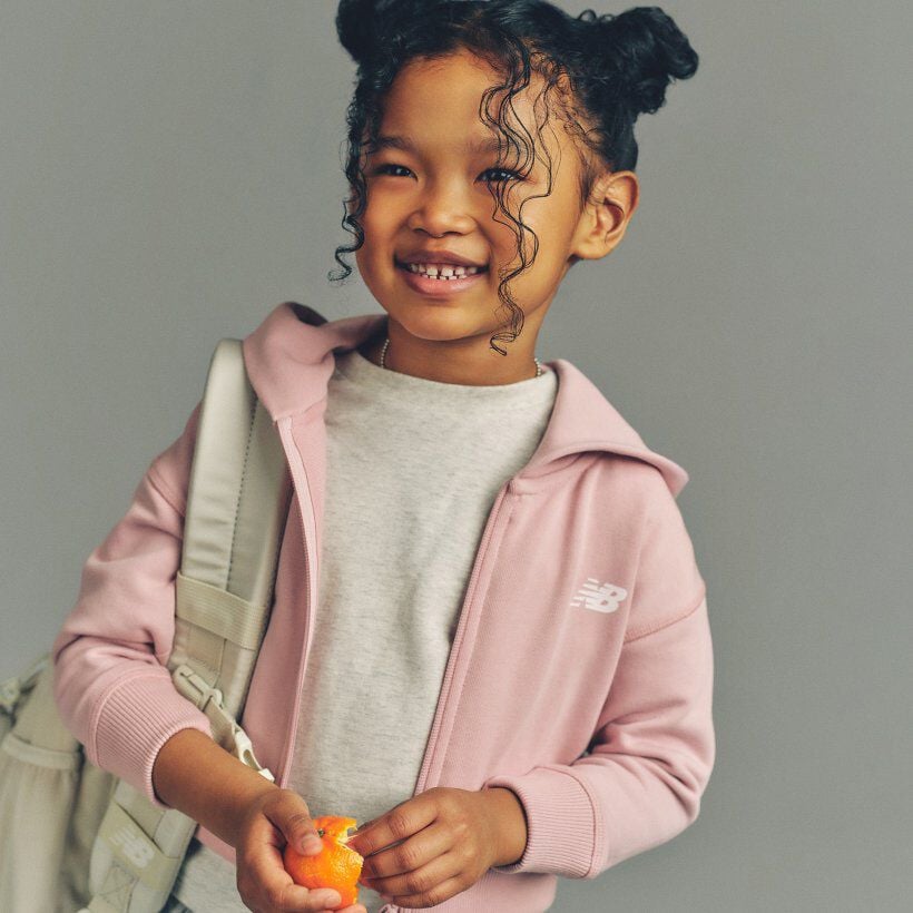 Young girl posing in front of a bike wearing New Balance 9060 sneakers 
