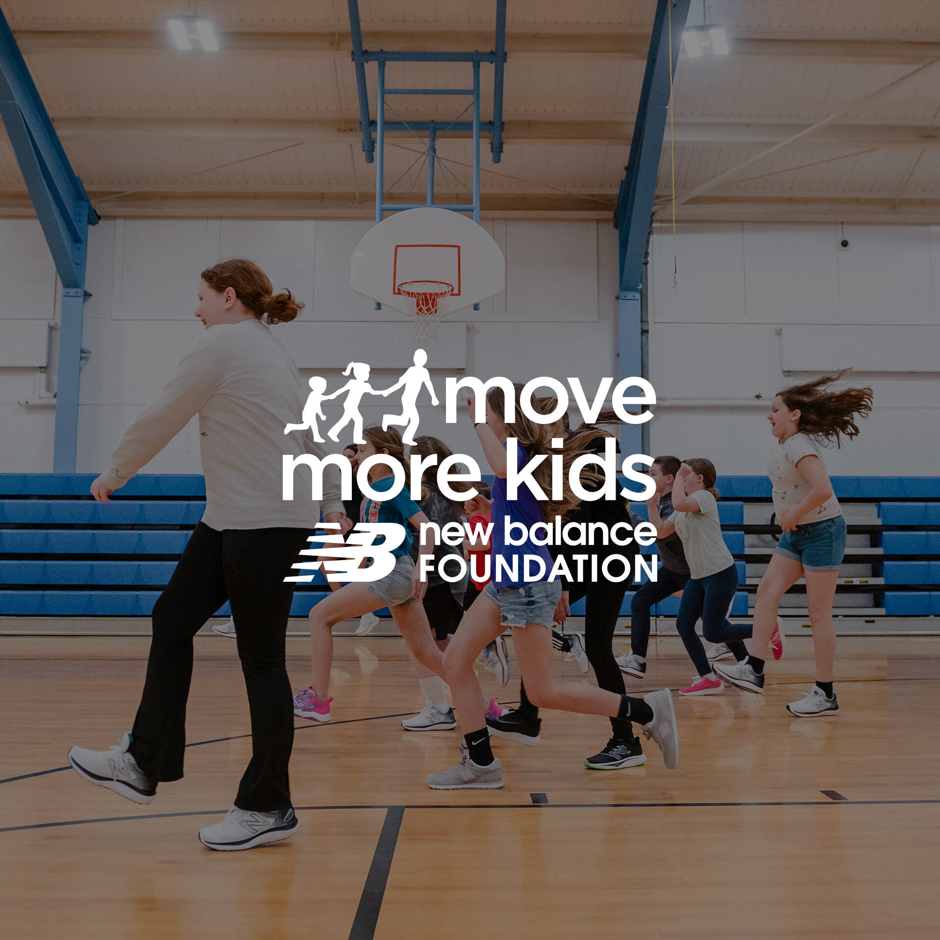 A group of light-skinned children happily running across a gymnasium floor. 