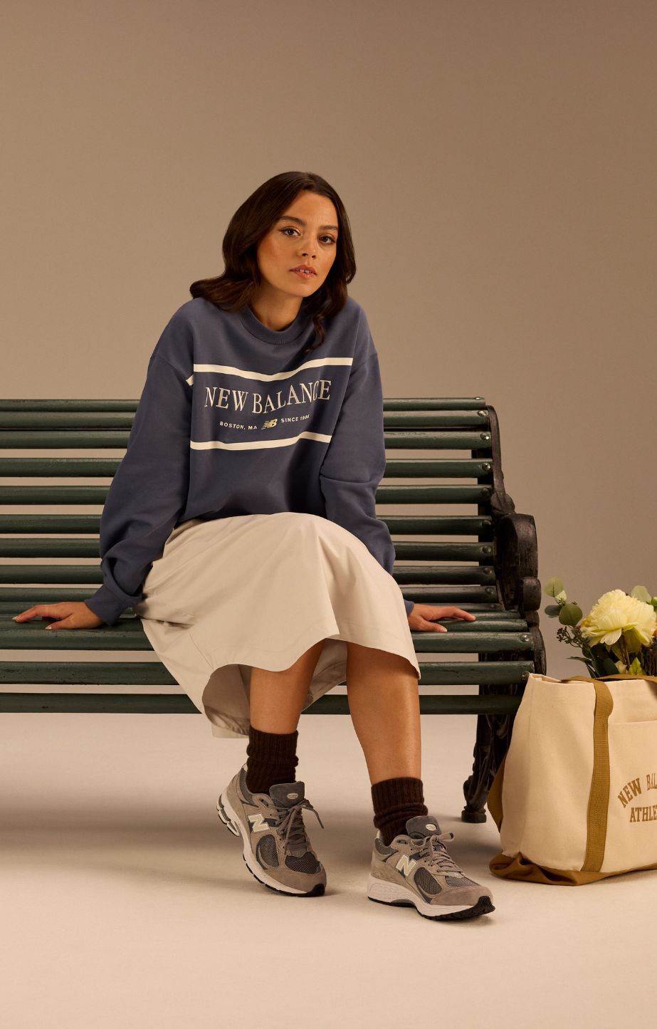 Woman sitting on a bench, wearing a new balance jumper