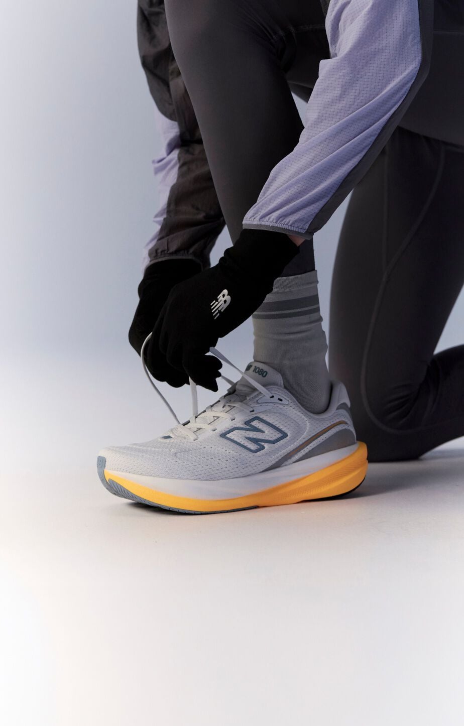 Knee down image of person tying a pair of 1080v15 running shoes 